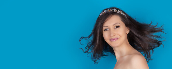 Portrait of a young woman with loose hair on a blue background. Sexy girl on a widescreen banner with copy space.