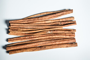 top horizontal view on pile of dry cinnamon sticks served on white table surface