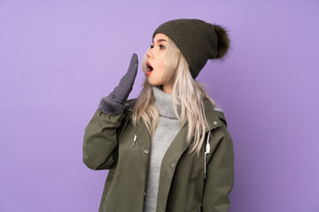 Teenager blonde girl with winter hat over isolated purple background yawning and covering wide open mouth with hand