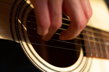 Close up photo of a girl plays the guitar at home. Warm evening sunlight and yellow tones. self-development at home