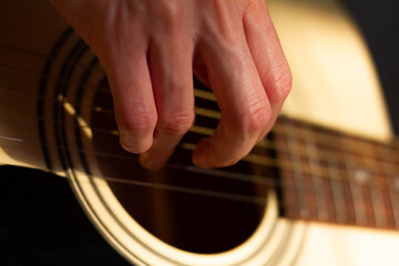 Close up photo of a girl plays the guitar at home. Warm evening sunlight and yellow tones. self-development at home - 359775186