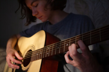 girl plays the guitar at home. Warm evening sunlight and yellow tones. self-development at home