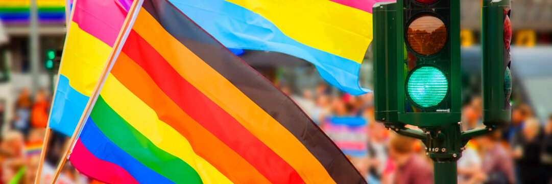Conceptual image of rainbow flag (LGBT movement) and green light on traffic lights. Horizontal image.