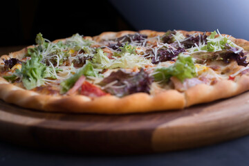closeup pizza on a tray, with vegetables and meat, in a rustic style. Unusual angle. Salad, vegetable pizza, meat lunch. Friendly pizza. The texture of the pizza. Food. Bad food. Carbohydrate food