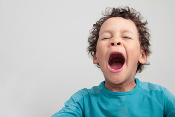 little boy yawning with open mouth on grey background stock photo