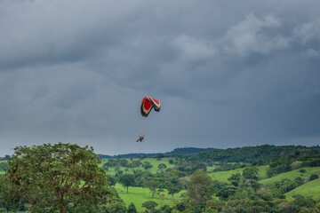 Paramotor em paisagem. Paramotor voando em céu nublado.