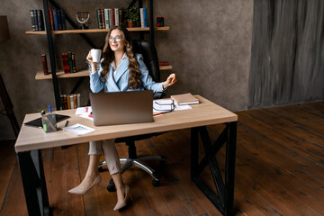 Beautiful business woman with cup of coffee at her office