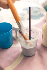 woman's hand painting pictures with paints on a day table