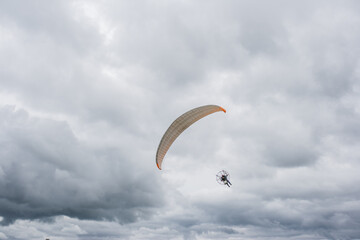 Pessoa voando de paramotor em céu nublado.