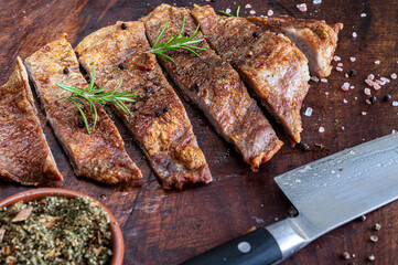 Close up of freshly cooked pork Secreto de ventresca pure iberico, iberian pig cut, with himalayan pink salt, pepper in grains, rosemary and a knife on a wooden board