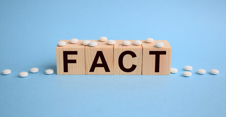 wooden cubes with text on a blue background with white pills, concept fact, confirmation in...