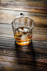 single malt whiskey with ice on the rock on wooden table top view