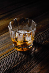 single malt whiskey with ice on the rock on wooden table top view