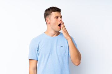 Young handsome man over isolated white background yawning and covering wide open mouth with hand