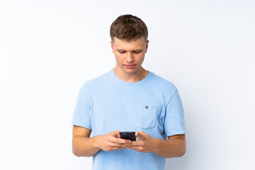 Young handsome man over isolated white background sending a message with the mobile