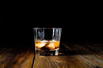 whiskey and ice on a wooden table dark background