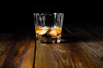 whiskey and ice on a wooden table dark background