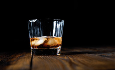 whiskey and ice on a wooden table dark background