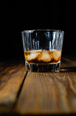 whiskey and ice on a wooden table dark background