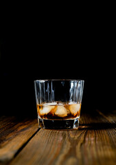 whiskey and ice on a wooden table dark background