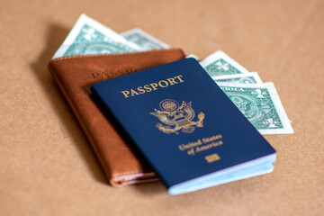 Concept photo of American tourists spending US Dollars and through travel after coronavirus. American passport, leather passport cover, and bank notes pictured.