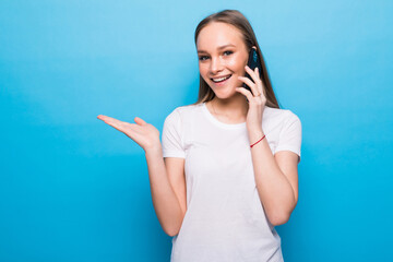 Young woman talking on the phone with open palm on a blue background