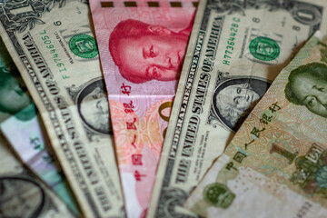 U.S.-China Trade War concept. Chinese Renminbi (yuan) currency banknotes with green US Dollar notes. Illustrates trade, commerce, imports, exports, exchange rates, and trade tensions.