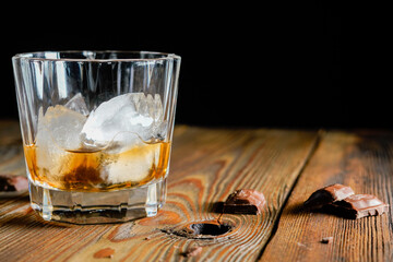 malt scotch whiskey with ice and chocolate on wooden table