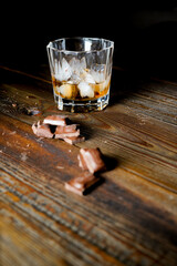 malt scotch whiskey with ice and chocolate on wooden table