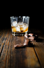 malt scotch whiskey with ice and chocolate on wooden table
