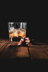 malt scotch whiskey with ice and chocolate on wooden table