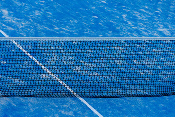 Paddle tennis net and blue court field background. Close up