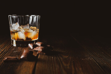 malt scotch whiskey with ice and chocolate on wooden table