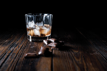 malt scotch whiskey with ice and chocolate on wooden table