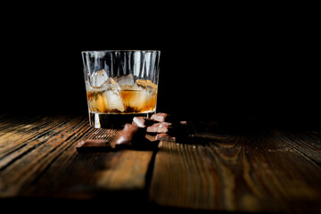malt scotch whiskey with ice and chocolate on wooden table