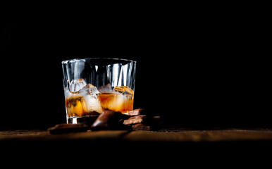 malt scotch whiskey with ice and chocolate on wooden table