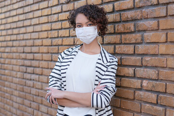 Obraz premium Portrait of a young woman with crossed arms wearing protective mask at street.