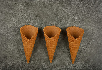 Three empty wafer ice cream cones on gray table