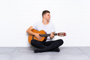Young handsome man with guitar looking side