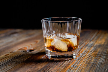 whiskey glass ice on the rock side view on wooden table dark background