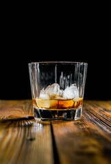 whiskey glass ice on the rock side view on wooden table dark background
