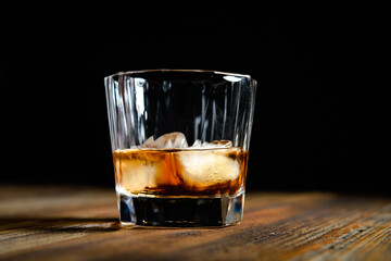 whiskey glass ice on the rock side view on wooden table dark background
