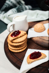 Biscuits with red jam on a wooden board on a piece of tissue