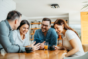 Cheerful group of friends looking pictures on smart phone.