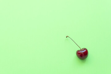 Fresh sweet cherry on green background. Healthy eating, minimalism concepts. Flat lay style with copy space for your text.