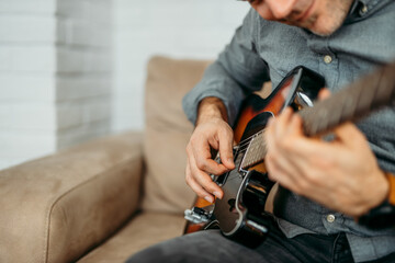 Smiling man playing guitar, close-up.