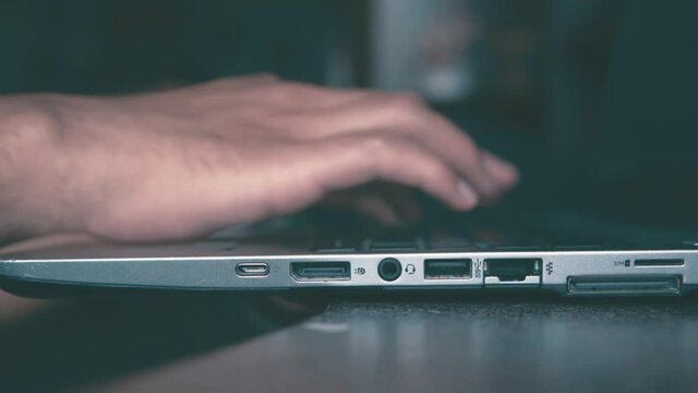 Manos de hombre escribiendo en la computadora port&aacute;til, sobre un escritorio, vista de cerca.