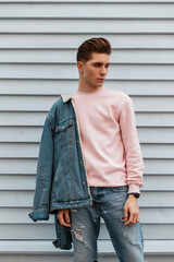 Good-looking young man with hairstyle with stylish blue denim jacket in pink fashionable sweatshirt...
