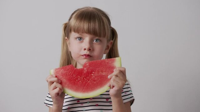 girl eating watermelon smiling on a white background