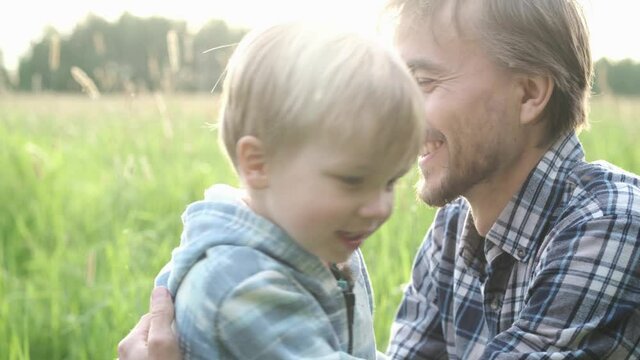 Cute toddler child boy hugging and kissing his father outdoor. Tenderness, love, dad and son relationship, fathers day concept. Happy family moments.